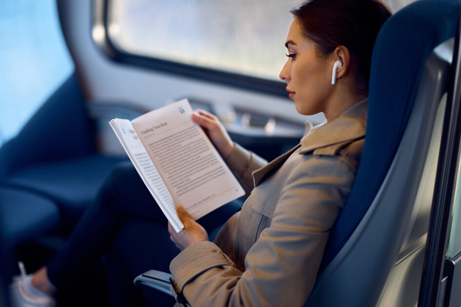 Person reading book on airplane with headphones